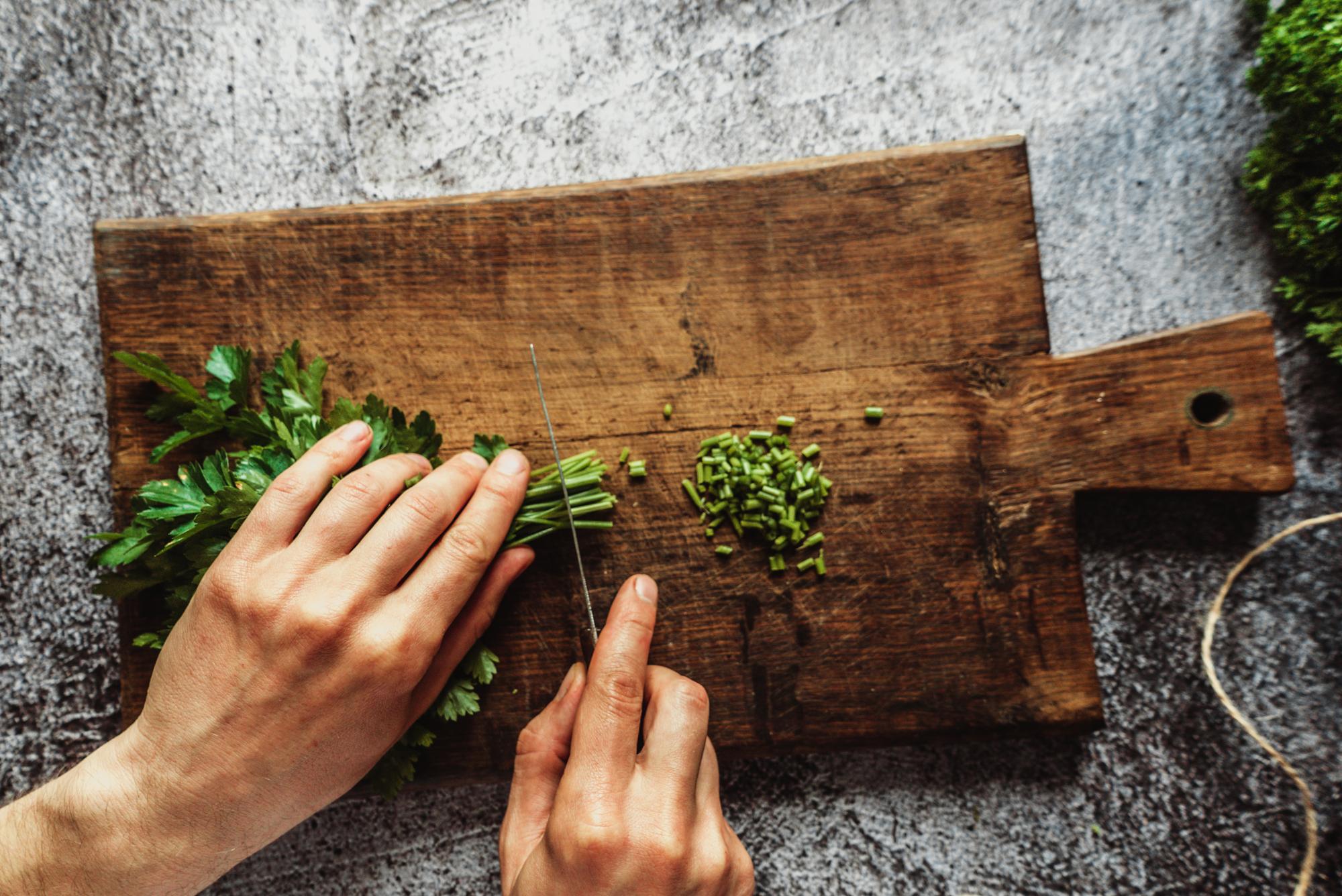 Chef affetta erbe fresche su tagliere artigianale